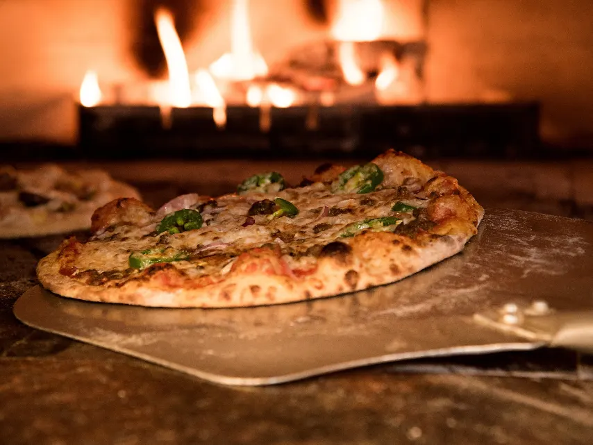Pizza assando no forno a lenha